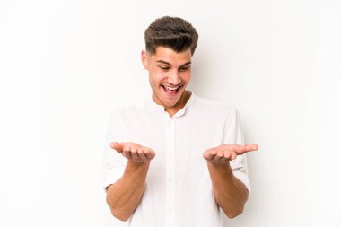 Beyaz arka planda izole edilmiş genç beyaz bir adam elinde avuç içi bir şeyle kameraya sunuyor..