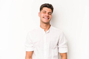 Beyaz arka planda izole edilmiş genç beyaz adam gülüyor ve gözlerini kapıyor, rahatlamış ve mutlu hissediyor..