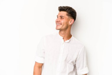 Beyaz arka planda izole edilmiş genç beyaz adam gevşemiş ve mutlu bir şekilde gülüyor, boynunda dişlerini gösteriyor..