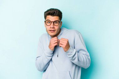 Kafkasyalı genç adam mavi arka planda izole edilmiş korkmuş ve korkmuş..