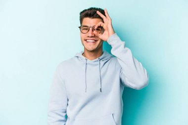 Kafkasyalı genç adam mavi arka planda izole edildi. Heyecanlı görünüyor..