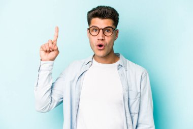 Kafkasyalı genç adam mavi arka planda izole edildi. Harika bir fikri var, yaratıcılık kavramı..