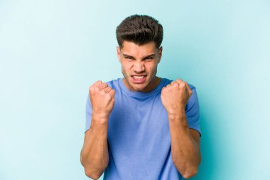 Mavi arka planda izole edilmiş genç beyaz adam gergin elleriyle çığlık atıyor..