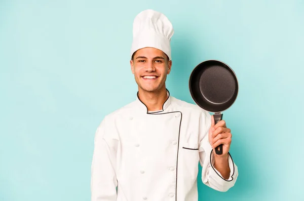 年轻的高加索厨师 拿着被蓝色背景隔离的飞盘 — 图库照片