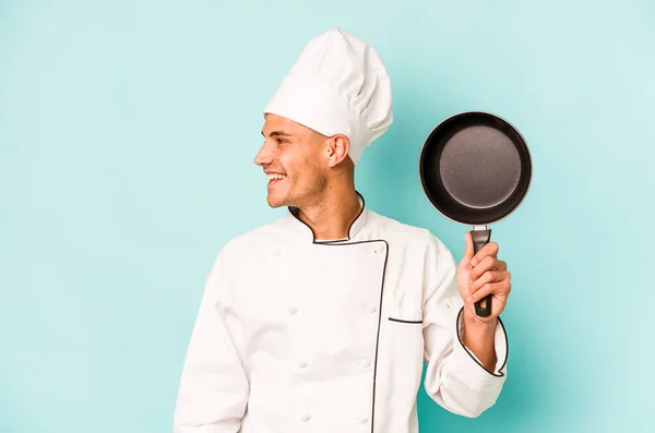 年轻的高加索厨师拿着蓝色背景的飞盘 面带微笑 开开开心心 令人愉快 — 图库照片