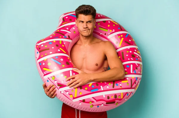 Young Caucasian Man Holding Inflatable Donut Isolated Blue Background Confused —  Fotos de Stock