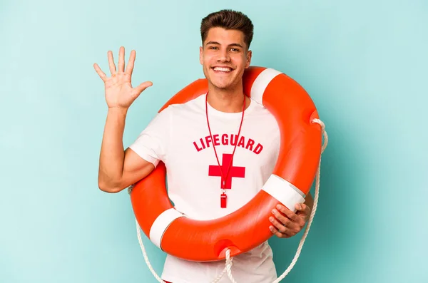 Young caucasian lifeguard isolated on blue background smiling cheerful showing number five with fingers.