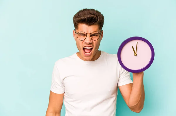 Young Caucasian Man Holding Clock Isolated Blue Background Screaming Very — Foto de Stock