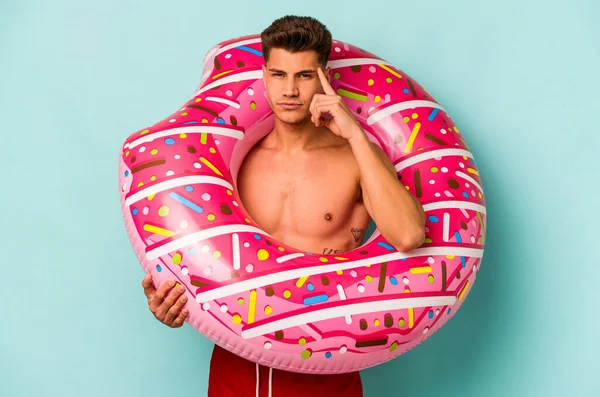 Young Caucasian Man Holding Inflatable Donut Isolated Blue Background Pointing —  Fotos de Stock