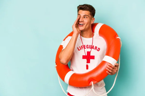 Young caucasian lifeguard isolated on blue background is saying a secret hot braking news and looking aside