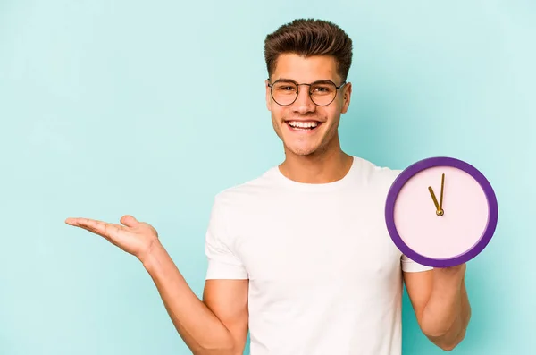 Young Caucasian Man Holding Clock Isolated Blue Background Showing Copy — ストック写真