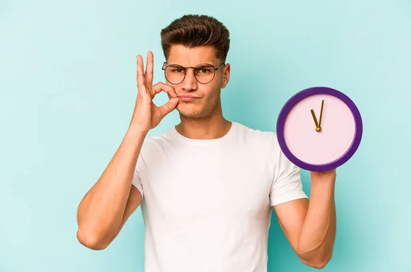 Young Caucasian Man Holding Clock Isolated Blue Background Fingers Lips — Stock Fotó