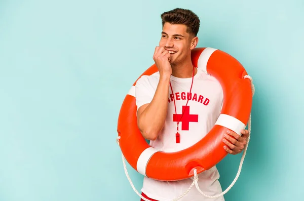Young caucasian lifeguard isolated on blue background relaxed thinking about something looking at a copy space.