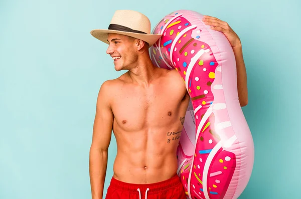 Young Caucasian Man Holding Inflatable Donut Isolated Blue Background Looks — Stock fotografie