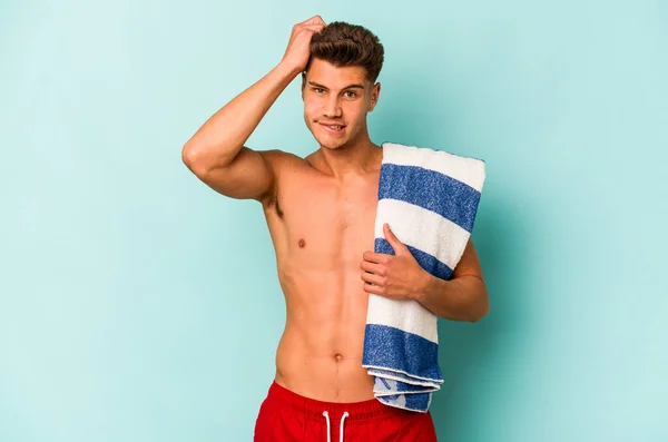 Young Caucasian Man Holding Beach Towel Isolated Blue Background Being — Stock Photo, Image