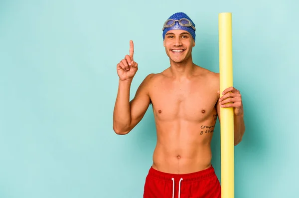 年轻的高加索游泳运动员 手握发泡棒 蓝色背景 带着第一指尖 — 图库照片