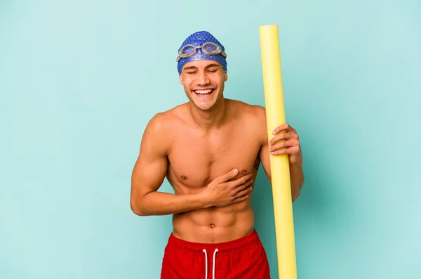 年轻的高加索游泳运动员 手持泡沫棒 与蓝色背景隔离 开怀大笑 玩得很开心 — 图库照片