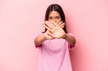 Pembe arka planda izole edilmiş genç İspanyol kadın inkar jesti yapıyor.