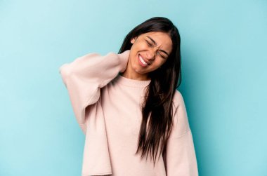 Genç İspanyol kadın, mavi arka planda izole edilmiş. Oturaklı yaşam tarzından dolayı boyun ağrısı çekiyor..