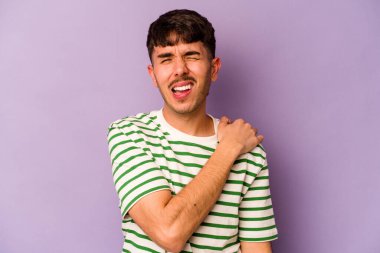 Mor arka planda izole edilmiş, omuz ağrısı olan genç beyaz bir adam..