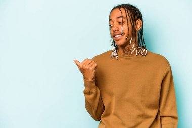 Genç Afrikalı Amerikalı adam mavi arka plan noktalarında izole edilmiş, başparmak uzakta, gülüyor ve kaygısız..