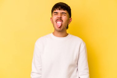Sarı arka planda izole edilmiş beyaz bir genç. Komik ve dost canlısı bir dil uzatıyor..