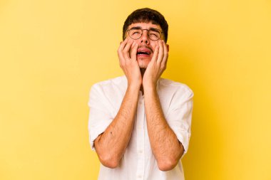 Kafkasyalı genç adam sarı arka planda izole edilmiş sızlanıyor ve ağlıyordu..