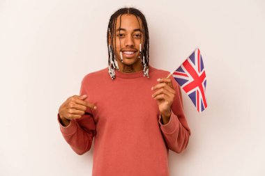 Beyaz arkaplanda İngiliz bayrağı taşıyan genç bir Afro-Amerikalı adam gömlek fotokopi alanını elle işaret ediyor, gururlu ve kendinden emin.
