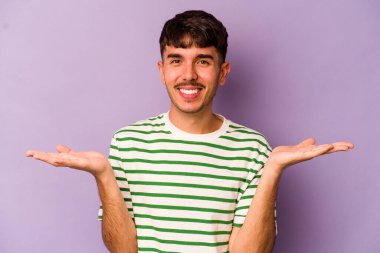 Mor arka planda izole genç beyaz adam kollarıyla ölçek yapar, mutlu ve kendinden emin hisseder..