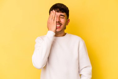 Sarı arka planda izole edilmiş genç beyaz adam yüzünün yarısını palmiye ile örterek eğleniyor..