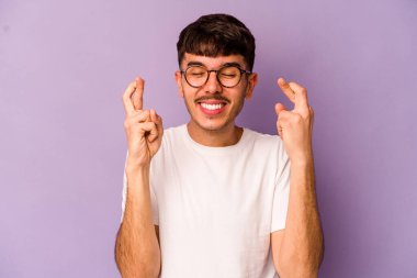 Mor arka planda izole genç beyaz adam şans dilemek için şans diliyor.