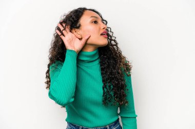 Beyaz arka planda izole edilmiş genç İspanyol kadın bir dedikoduyu dinlemeye çalışıyor..