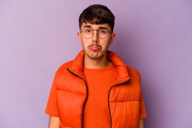 Mor arka planda izole edilmiş genç beyaz adam üzgün, ciddi yüz, sefil ve hoşnutsuz hissediyor.