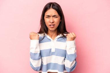 Pembe arka planda izole edilmiş genç İspanyol kadın kameraya yumruğunu, agresif yüz ifadesini gösteriyor..