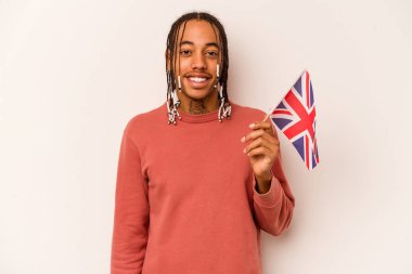 Beyaz arka planda izole edilmiş İngiliz bayrağı tutan genç Afrikalı Amerikalı adam gülüyor ve eğleniyor..