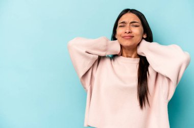 Genç İspanyol kadın mavi arka planda izole edilmiş kafasının arkasına dokunuyor, düşünüyor ve bir seçim yapıyor..