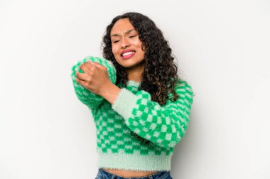 Genç İspanyol kadın beyaz arka planda izole edilmiş, dirsek masajı yapıyor, kötü bir hareketin ardından acı çekiyor..