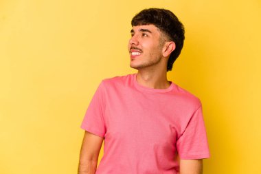 Sarı arka planda izole edilmiş genç beyaz adam gevşemiş ve mutlu gülüyor, boynunda dişlerini gösteriyor..