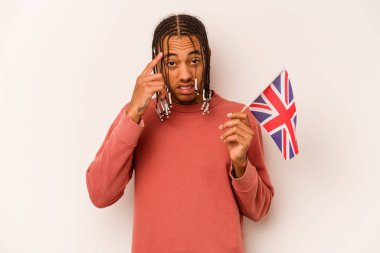 Beyaz arka planda izole edilmiş İngiliz bayrağı tutan genç Afrikalı Amerikalı adam işaret parmağıyla yaptığı hayal kırıklığı jestini gösteriyor..
