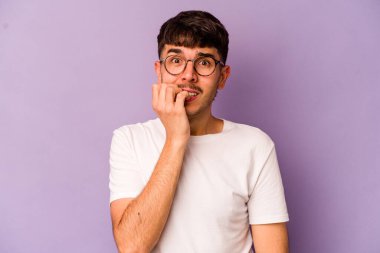 Mor arka planda izole edilmiş, tırnak yiyen, gergin ve endişeli genç bir beyaz adam..