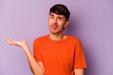 Mor arka planda izole edilmiş genç beyaz adam sorgulama sırasında omuz silkiyor ve şüphe duyuyor..