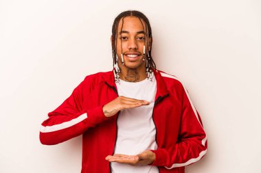 Beyaz arka planda izole edilmiş genç Afrikalı Amerikalı iki eliyle bir şey tutuyor, ürün sunumu..