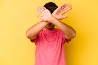 Sarı arka planda izole genç beyaz adam iki kolu çapraz tutuyor, inkar kavramı.