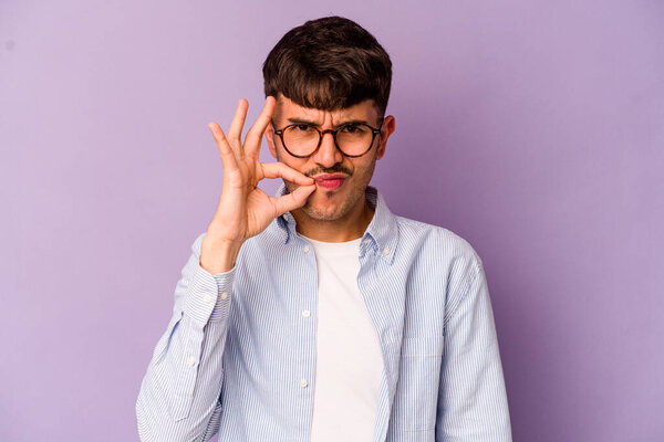 Young caucasian man isolated on purple background with fingers on lips keeping a secret.