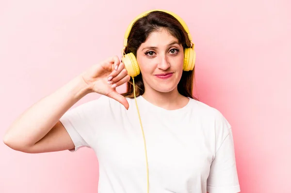 Mujer Caucásica Joven Escuchando Música Aislada Sobre Fondo Rosa Mostrando —  Fotos de Stock