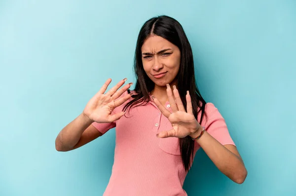 青の背景に孤立した若いヒスパニック系の女性が嫌悪感のジェスチャーを示す誰かを拒否 — ストック写真