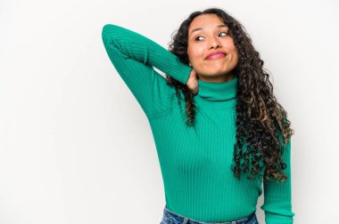 Beyaz arka planda izole edilmiş genç İspanyol kadın kafasının arkasına dokunuyor, düşünüyor ve bir seçim yapıyor..