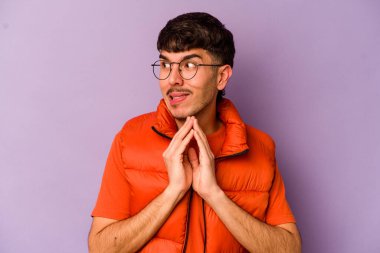 Mor arka planda izole edilmiş genç beyaz adam dua ediyor, bağlılık gösteriyor, dindar biri ilahi ilham arıyor..
