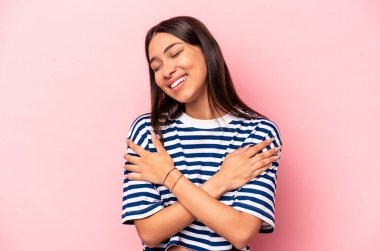 Genç İspanyol kadın pembe arka planda izole edilmiş gülüyor ve eğleniyor.