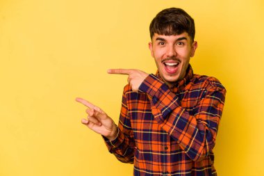Sarı arka planda izole edilmiş genç beyaz adam işaret fişekleriyle işaret ederek heyecanlanıyor..